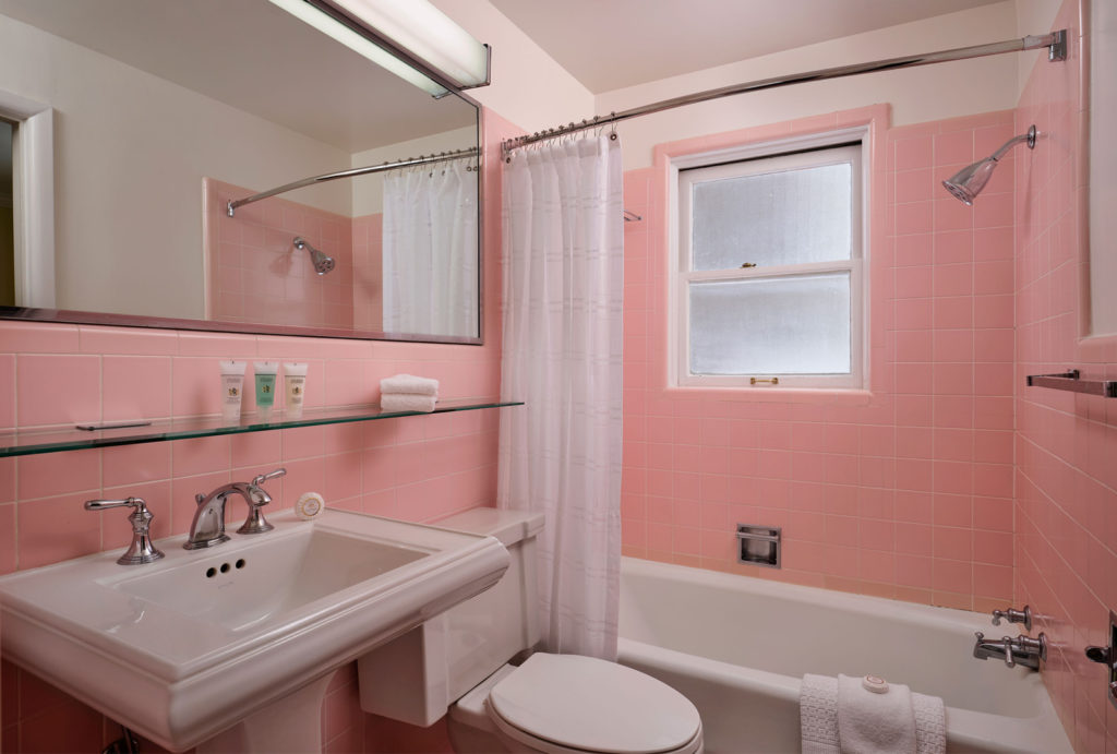 Pink bathroom with toilet, sink, mirror, and shower at Little America Wyoming.